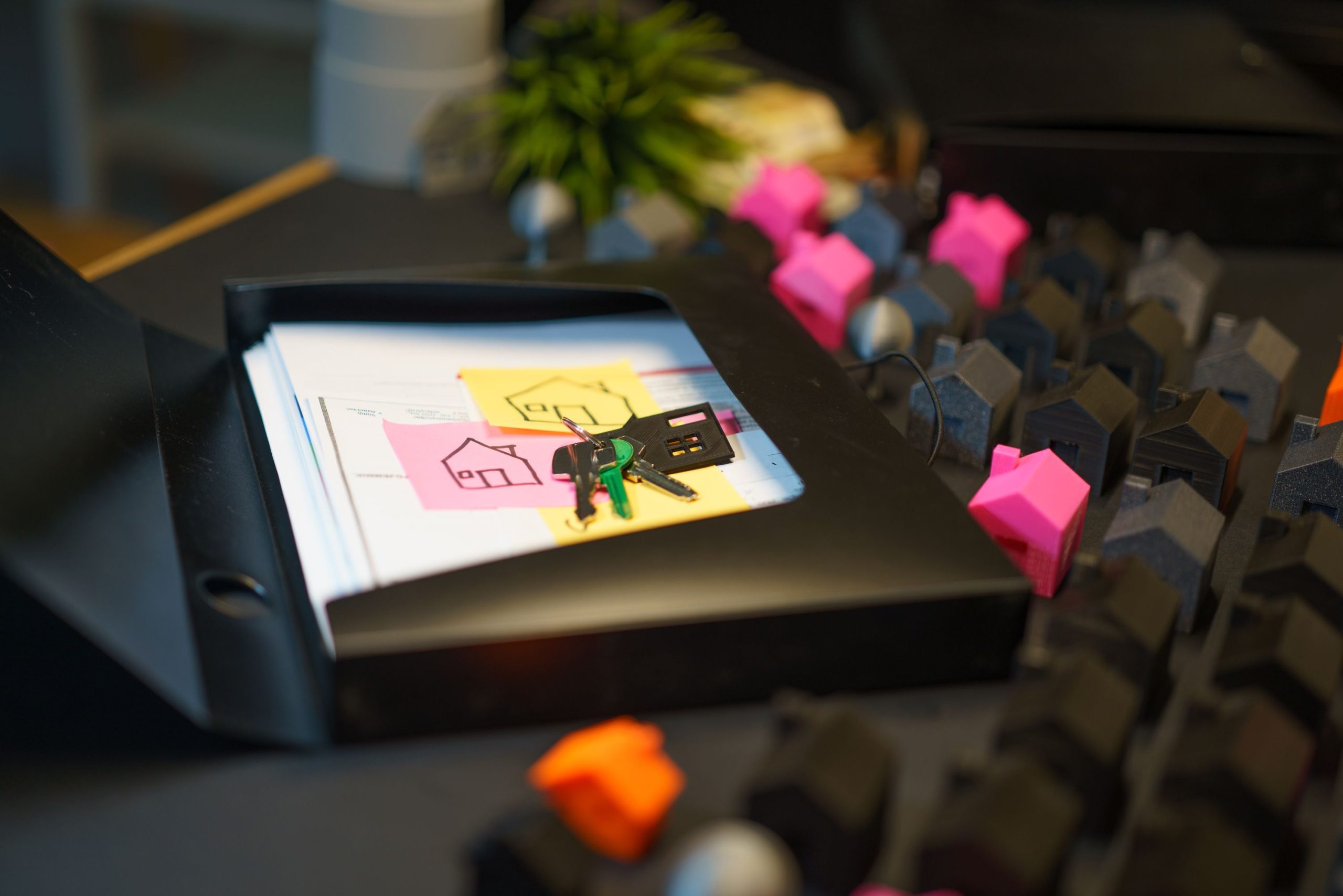 Keys and property documents on a desk surrounded by miniature house models